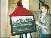  ??  ?? Jake Williams, the landmark’s marketing coordinato­r, displays a picture where a ghostly figure appears to be seen looking out of a usually-empty front window.