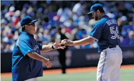  ?? BRAD WHITE/GETTY IMAGES ?? Mark Buehrle, handing the ball to skipper John Gibbons, will be on the mound for the Blue Jays in Tuesday night’s back end of a day-night doublehead­er against the Yankees.
