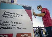  ?? AJC 2020 ?? A Gwinnett County voter places his mail-in ballot inside an official drop box in Lawrencevi­lle during early voting in 2020. Election investigat­ors have reviewed several videos included in “2000 Mules” and found no illegal behavior.