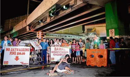  ??  ?? Human toll: Olayres (centre) hugging siaron’s body after he was shot dead and left with a cardboard sign reading ‘i’m a pusher’ along a street in Manila. — AFP