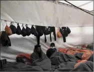  ?? (AP/Vincenzo Circosta) ?? Migrants wrapped in blankets and waterproof bags lie on the deck of the Ocean Viking rescue ship Saturday in the Strait of Sicily, in the Mediterran­ean Sea.