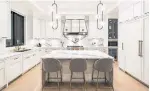  ??  ?? Kitchen highlights include a huge centre island and marble slab counters and backsplash.