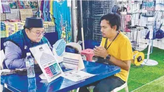  ?? – SYED AZAHAR SYED OSMAN /THESUN ?? FULFILLING OBLIGATION ... A shopper paying zakat (tithe) at an Aidilfitri bazaar in Jalan Tuanku Abdul Rahman, Kuala Lumpur.