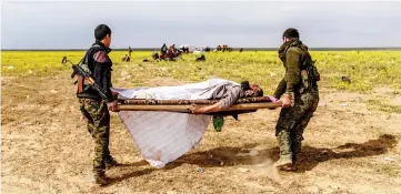  ??  ?? Members of the Kurdish-led Syrian Democratic Forces carry a man suspected of being an Islamic State group fighter near a screening area after he left the IS last holdout of Baghouz, in the eastern Syrian Deir Ezzor province. — AFP photo