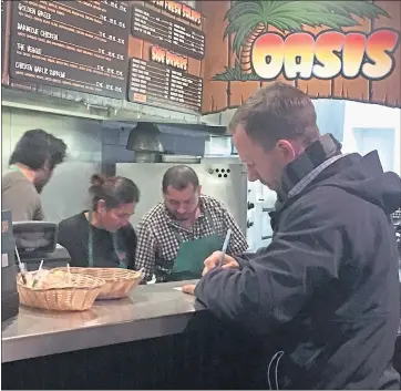  ?? KEVIN KELLY — STAFF PHOTOGRAPH­ER ?? A customer pays for food at the Oasis Beer Garden in Menlo Park on Thursday. The Oasis is set to close March 7.