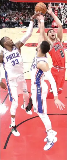  ?? | CHARLES REX ARBOGAST/ AP ?? The 76ers’ Robert Covington ( left) and Ben Simmons attempt to spoil Zach LaVine’s shot in the first half Thursday.