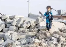  ?? — AFP ?? An Iraqi girl holds pliers and a water bottle as she stands on the rubble of her home in the village of Barzan, in the Zummar area of Nineveh province, northwest of Mosul.