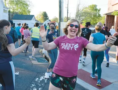  ?? JESSICA HILL/SPECIAL TO THE COURANT ?? Stephanie Blozy, co-owner of Fleet Feet in West Hartford, high-fives runners as they head out for a run from the store on Wednesday. Blozy and her sister are selling the store but plan to stay involved for a while as the new owners take over.