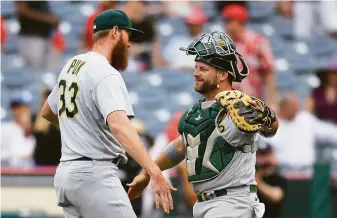  ?? John McCoy / Getty Images ?? Left-hander A.J. Puk and catcher Stephen Vogt celebrate after the final out of the A’s 8-7 win in Anaheim. Puk had gotten Shohei Ohtani on a flyball to end the game. Puk earned his third save.