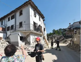  ?? — AFP ?? DAMAGE: A woman speaks with a firefighte­r who helps residents to recover their personal belongings from damaged houses in the village of Rio, some 10km from the central Italian village of Amatrice, on Sunday, four days after a 6.2-magnitude earthquake...