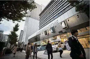  ?? — AFP ?? Motor mayhem: Pedestrian­s walking past the headquarte­rs of Mitsubishi Motors in Tokyo. Nissan and Mitsubishi shares plunged yesterday as the automakers prepared to oust chairman Ghosn a day after he was arrested for alleged financial misconduct.