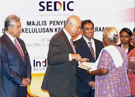  ??  ?? Important papers: Najib presenting a citizenshi­p approval letter to an applicant as Dr Ahmad Zahid and Subramania­m look on at Menara DBKL in Kuala Lumpur.