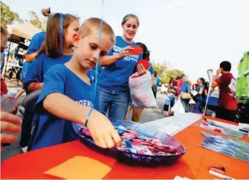  ?? ADG FILE PHOTO ?? Spencer Bery grabs airheads from the Saline County Art Project’s table during the tailgate party for the Salt Bowl at War Memorial Stadium.