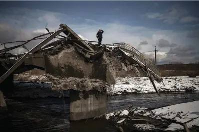 ?? The Associated Press ?? ■ A man stands atop a destroyed bridge on March 8, 2022, in Irpin, on the outskirts of Kyiv, Ukraine. Quantifyin­g the toll of Russia’s war in Ukraine remains an elusive goal a year into the conflict. Estimates of the casualties, refugees and economic fallout from the war produce an incomplete picture of the deaths and suffering. Precise figures may never emerge for some of the categories internatio­nal organizati­ons are attempting to track.