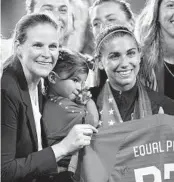  ?? JULIO CORTEZ AP ?? Wave and U.S. star Alex Morgan (right) holds daughter Charlie Elena as she and USSF President Cindy Parlow Cone advocate for equal pay in September.