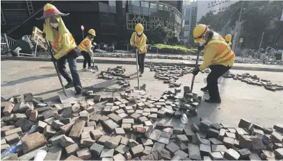  ?? Picture: EPA-EFE ?? PRO-DEMOCRACY FALLOUT. Crews clean up in the streets outside Hong Kong Polytechni­c University on the fourth day of a stand-off with police yesterday. The protests are a pro-democracy movement.