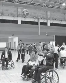  ?? ZOU HONG / CHINA DAILY ?? Govinda Prasad Bhattarai (right), a Nepalese diplomat, tries wheelchair basketball during a New Year reception held by the China Disabled Persons’ Federation in Beijing on Tuesday.