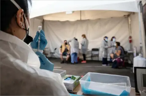  ?? Mike Kai Chen/The New York Times ?? A phlebotomi­st works at a COVID-19 vaccinatio­n site Monday in the Mission District of San Francisco. Small groups of vaccinated people can get together without much worry about infecting each other, experts said. But going mask-free in public will depend on many factors.