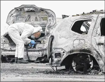  ?? LAURENT CIPRIANI / AP ?? An investigat­ing French police officer takes photograph­s on the highway where thieves robbed an armored truck loaded with gold, Monday in Dardilly in central France. French police say a manhunt is underway for four thieves who have stolen dozens of...