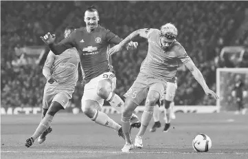  ??  ?? Manchester United’s Zlatan Ibrahimovi­c (left) challenges St Etienne’s Kevin Malcuit at Old Trafford in Manchester. — Reuters photo