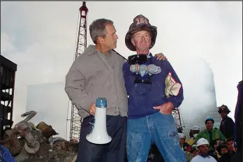  ?? AP Photo/Doug Mills, File ?? President George W. Bush, left, stands with New York City firefighte­r Bob Beckwith on a burnt fire truck in front of the World Trade Center during a tour of the devastatio­n, Sept. 13, 2001