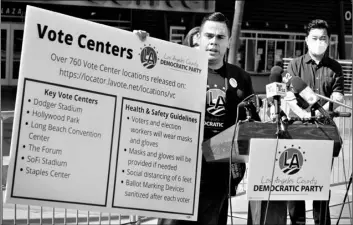  ?? AP Photo/Damian Dovarganes ?? In this Oct. 1 file photo, Los Angeles County Democratic Party Chair Mark J. Gonzalez (center) flanked by Los Angeles City Councilmem­ber David Ryu (right) and others, holds a banner with key vote center locations and social distancing instructio­ns at a news conference outside Staples Center in Los Angeles.