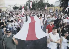  ??  ?? 0 Protesters carry the opposition flag in Minsk