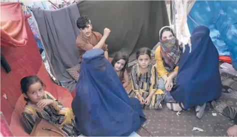  ?? RAHMAT GUL/AP ?? Displaced school teacher Nilofar, in a burqa on the left, sits in her tent with others Friday at a park in Kabul amid the Taliban advance.