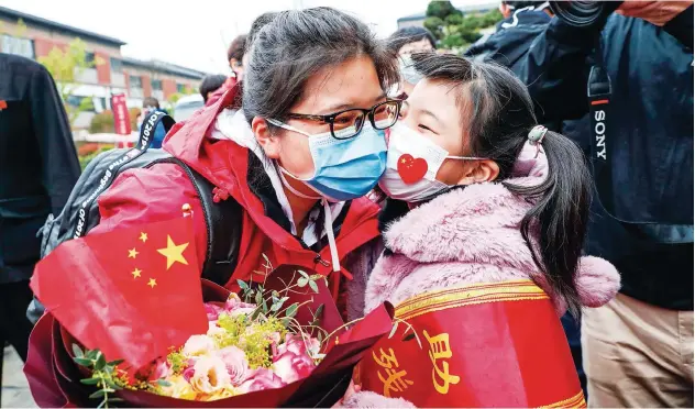  ?? Agence France-presse ?? ↑ A member of a medical assistance team from Huaian being welcomed by her daughter after returning home from Wuhan to help the coronaviru­s recovery effort in Jiangsu province on Wednesday.