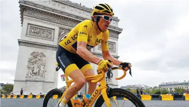  ?? (Reuters) ?? TEAM SKY RIDER Geraint Thomas of Britain, wearing the overall leader’s yellow jersey, passes the Arc de Triomphe in Paris yesterday on his way to capturing his first Tour de France title.