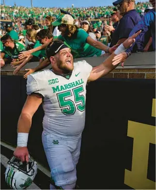  ?? MICHAEL CONROY/AP ?? Marshall offensive lineman Trent Holler celebrates with fans after the team’s 26-21 win over Notre Dame in a game Saturday in South Bend, Indiana.