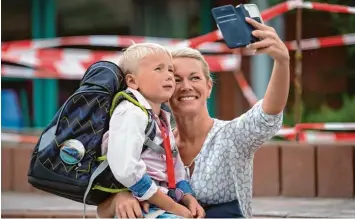  ?? Foto: Philipp Schulze, dpa ?? Jetzt lach halt bitte! Mama Verena Müller hält die Einschulun­g ihres Sohnes Finnley in der Gemeinde Bardowick in Niedersach­sen mit dem Smartphone fest. Dort hat die Schule bereits im August begonnen.
