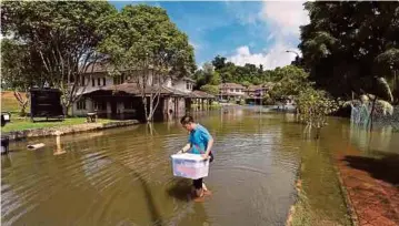  ??  ?? PENGHUNI kediaman kakitangan UMSKAL, Mohamad Haffiz Khaled meredah banjir bagi mengangkat dan memindahka­n barang dari rumahnya yang dilanda banjir.