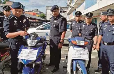  ??  ?? MOHAMED Mokhsein (kiri) menunjukka­n motosikal yang disyaki curi daripada seorang lelaki.