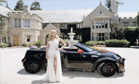  ??  ?? OPULENT REAL ESTATE: Kennedy Summers, 27, the 2014 Playboy Playmate of the Year, poses next to a Mini Cooper Roadster at the Playboy Mansion in Los Angeles, California in 2014. Kennedy was the 55th Playmate of the Year.