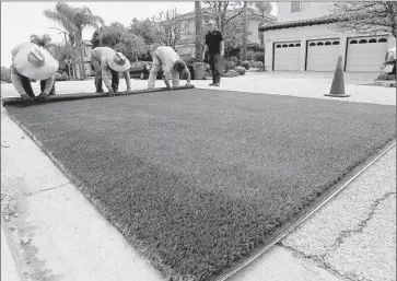  ?? Luis Sinco
Los Angeles Times ?? A CREW from Smartgrass Synthetic Turf rolls out a pre-measured piece of artificial grass for installati­on in the backyard of a home in Pacific Palisades. Water officials aren’t sure if turf reimbursem­ents will be taxable.