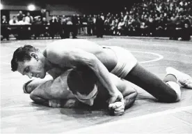  ??  ?? OU's Danny Hodge maneuvers Iowa's Tom Shaheen into the fall with a bar-arm and headlock during a match on March 8, 1957, in Norman. [AP PHOTO/FILE]