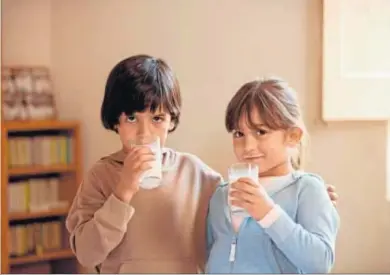  ??  ?? Dos niños fotografia­dos bebiendo un vaso de leche.