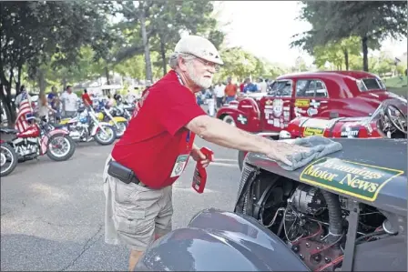  ?? PHOTOS BY YALONDA M. JAMES/THE COMMERCIAL APPEAL ?? Tom Lawson of Lithonia, Ga., a support team member, cleans Dave Haverty’s 1937 Ford following a leg in “The Great Race,” a classic car road rally that stopped Wednesday night at Municipal Park in Germantown. The race began in St. Paul, Minn., last...