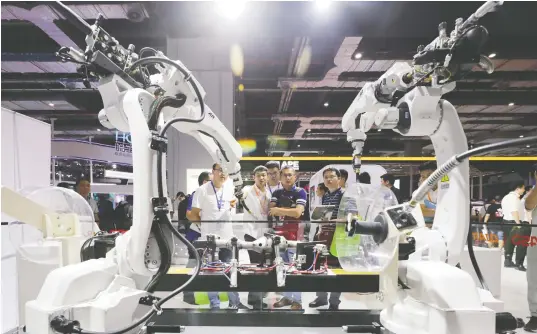  ??  ?? 第21届中国国际工业­博览会上，参观者在观看一组焊接­机器人的现场作业演示
新华社图