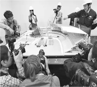  ?? — AFP photo ?? An official of the Japan Sports Council (right) speaks next to a model of the new National Stadium which is under constructi­on in Tokyo in this Oct 13, 2017 file photo. The stadium will host the opening ceremony and athletics events during the 2020...