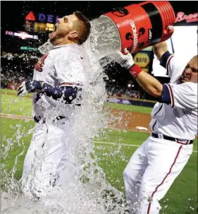  ?? David Goldman
/
The Associated Press ?? Atlanta’s Freddie Freeman is doused with water by Eric Hinske after Freeman hit a home run to help the Braves beat the Marlins 4-3 to clinch at least a wild-card berth.