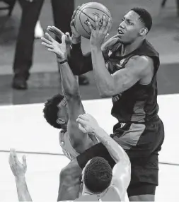  ?? Noah K. Murray / Associated Press ?? Knicks guard RJ Barrett shoots over a pair of Raptors during the second half. Barrett had a double-double with 25 points and 12 rebounds in the win.