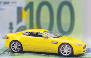  ?? FOTO: DPA ?? Modell eines Sportwagen­s mit Banknoten: Durch den Wechsel zu einem günstigere­n Autoversic­herer lassen sich schon mal ein paar Hundert Euro sparen. Beim Preisvergl­eich sollten Verbrauche­r aber nicht nur auf die Prämien schauen, sondern auch auf die Leistungen.