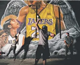  ?? FOTO: AFP ?? Aocionados saltan nelices delante de un mural Con la imagen de su ídolo Kobe Bryant y su hija, nallecidos en enero en un Accidente Aéreo.