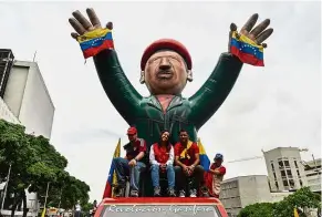  ??  ?? Making a statement: Maduro supporters riding on top of a vehicle with an inflatable figure of Chavez during a rally in Caracas. — AFP