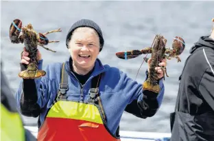  ?? MB WHITCOMB ?? Donelda Macaskill shows off a couple of freshly caught lobsters in this recent picture take at the Englishtow­n wharf. Looking on is worker Robert Campbell. Macaskill is looking to sell Donelda’s Puffin Boat Tours, which she has operated for 26 years.