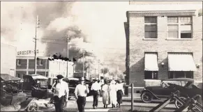  ?? Associated Press ?? In this photo provided by the Department of Special Collection­s of McFarlin Library at the University of Tulsa, two armed men walk away from burning buildings as others walk in the opposite direction during the June 1, 1921, Tulsa Race Massacre in Tulsa, Okla.