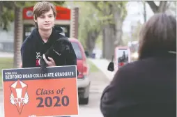  ?? MICHELLE BERG ?? Bedford Road Collegiate Grade 12 student Zachary Newton picks up a “Class of 2020” sign on May 20.