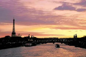  ?? —AFP ?? RISKY RIVER A boat floats down the Seine in Paris as the Eiffel tower looms in the background on March 21. The French capital is asking houseboats and restaurant­s lining the famous waterway not to dump their waste in it so that Olympic open water swimmers and triathlon athletes can swim safely during the Summer Games from July 26 to Aug. 11.